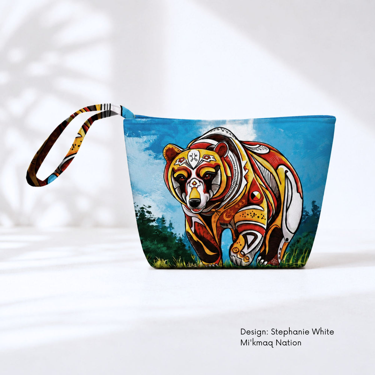 Canvas pouch featuring a patterned red, orange, black and white bear walking forward against a blue sky and dark green vegetation.