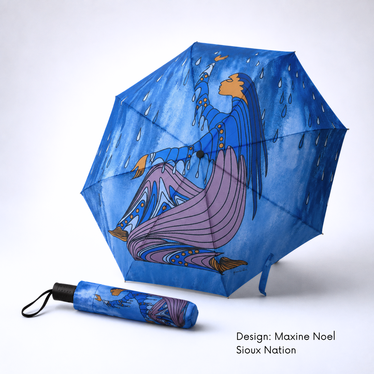 A blue folding umbrella shown open and closed on a light gray studio background. The open umbrella features Maxine Noel’s Rainmaker artwork with a flowing figure and falling rain.