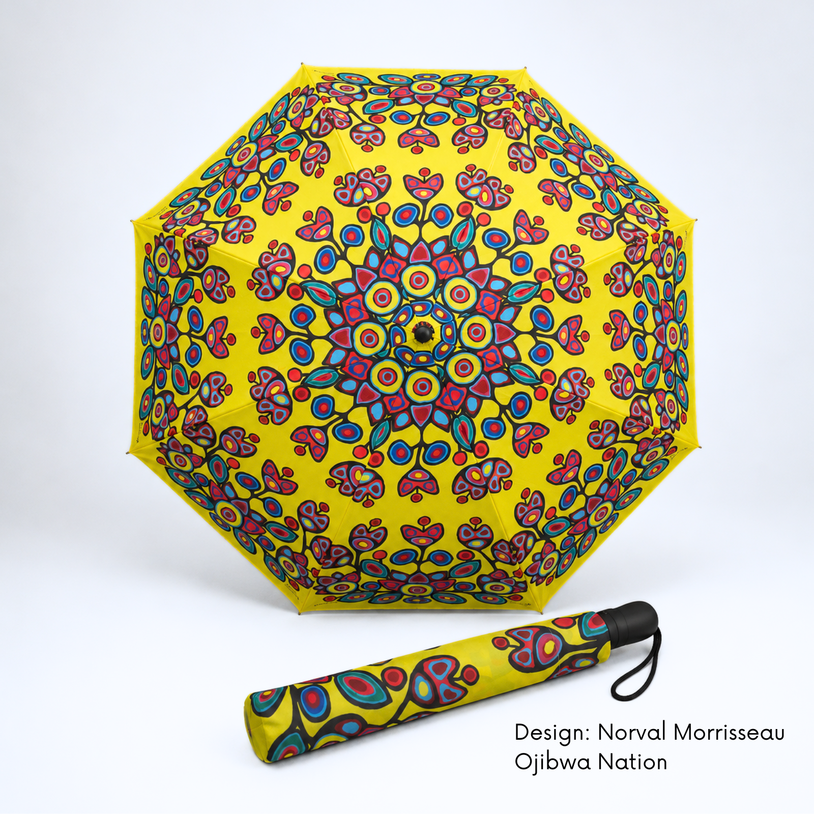 A bright yellow folding umbrella featuring Norval Morrisseau’s colourful Floral on Yellow artwork shown open with its matching folded version below on a white studio background. Text at the bottom right reads 'Design: Norval Morrisseau Ojibwa Nation'.