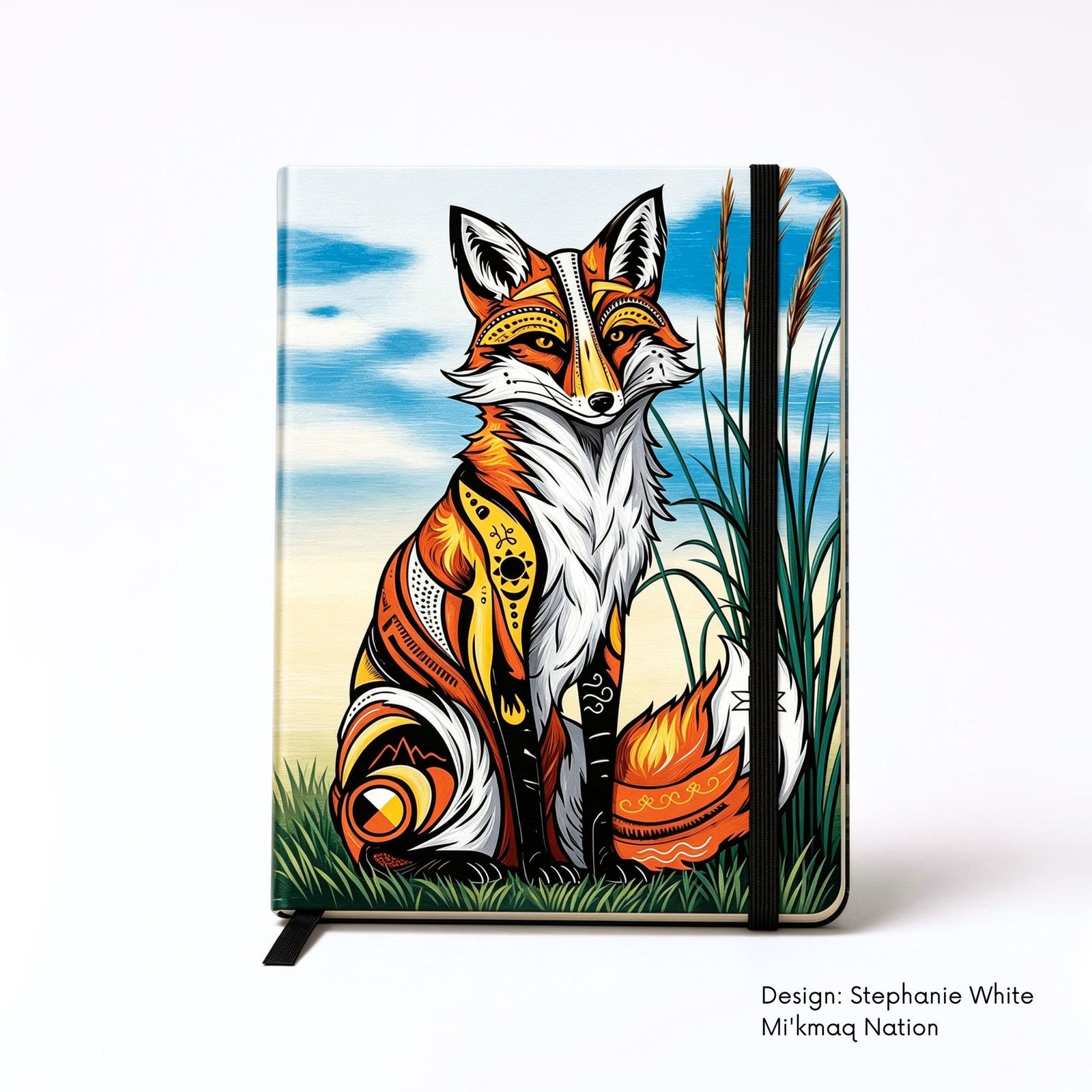 Hardcover journal featuring a seated red fox filled with bold red, yellow, black and white symbols, surrounded by grass and tall reeds beneath a blue sky.