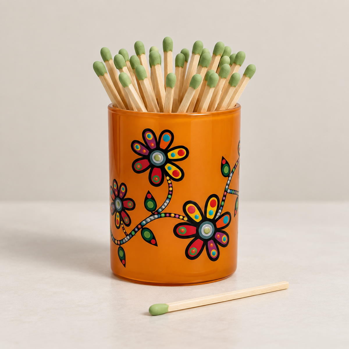 Glass match holder featuring John Rombough's Flowers artwork, filled with long matches.