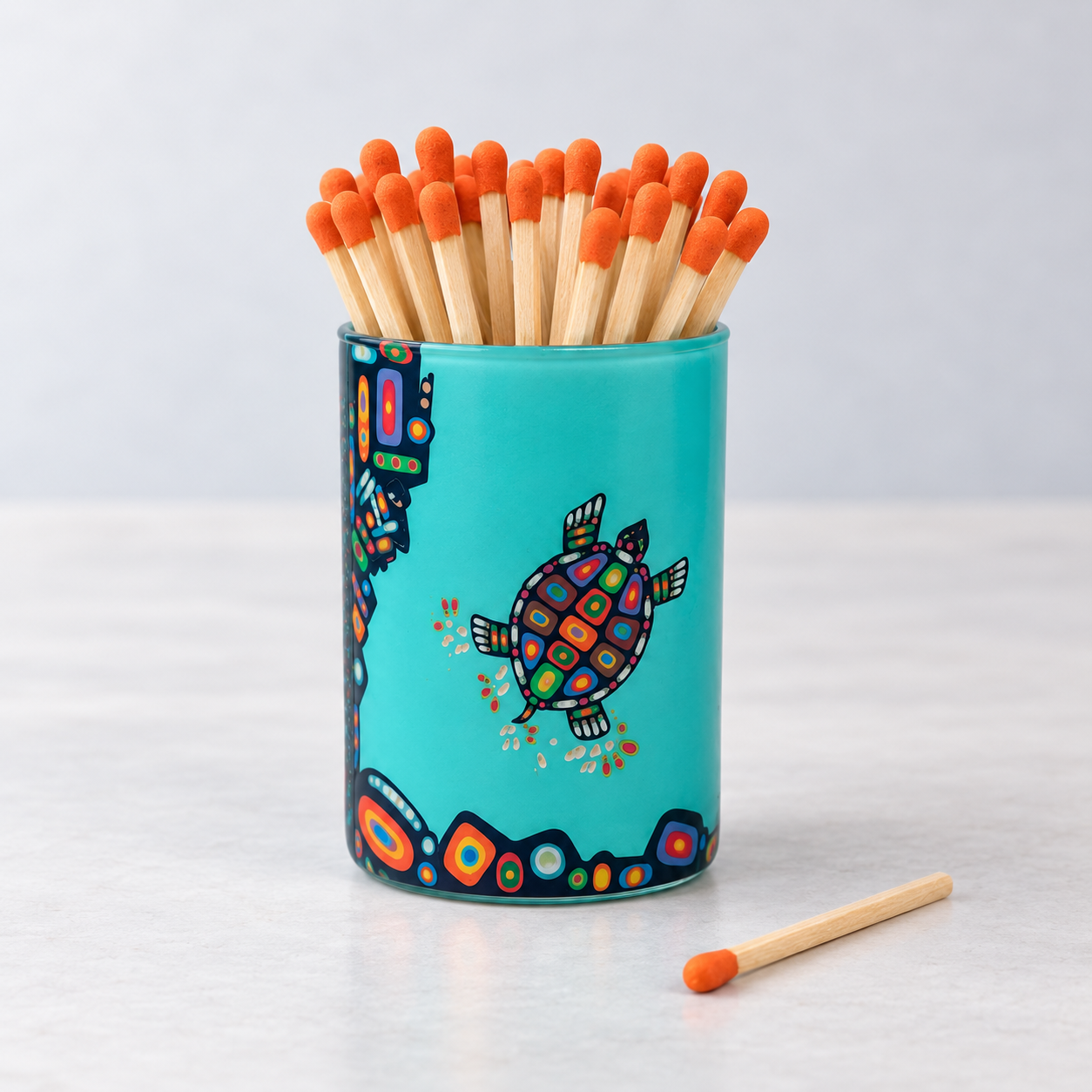 Glass match holder featuring John Rombough's Turtle artwork, filled with long matches.
